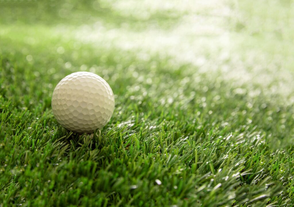 Golfball on green grass golf course, close up view.